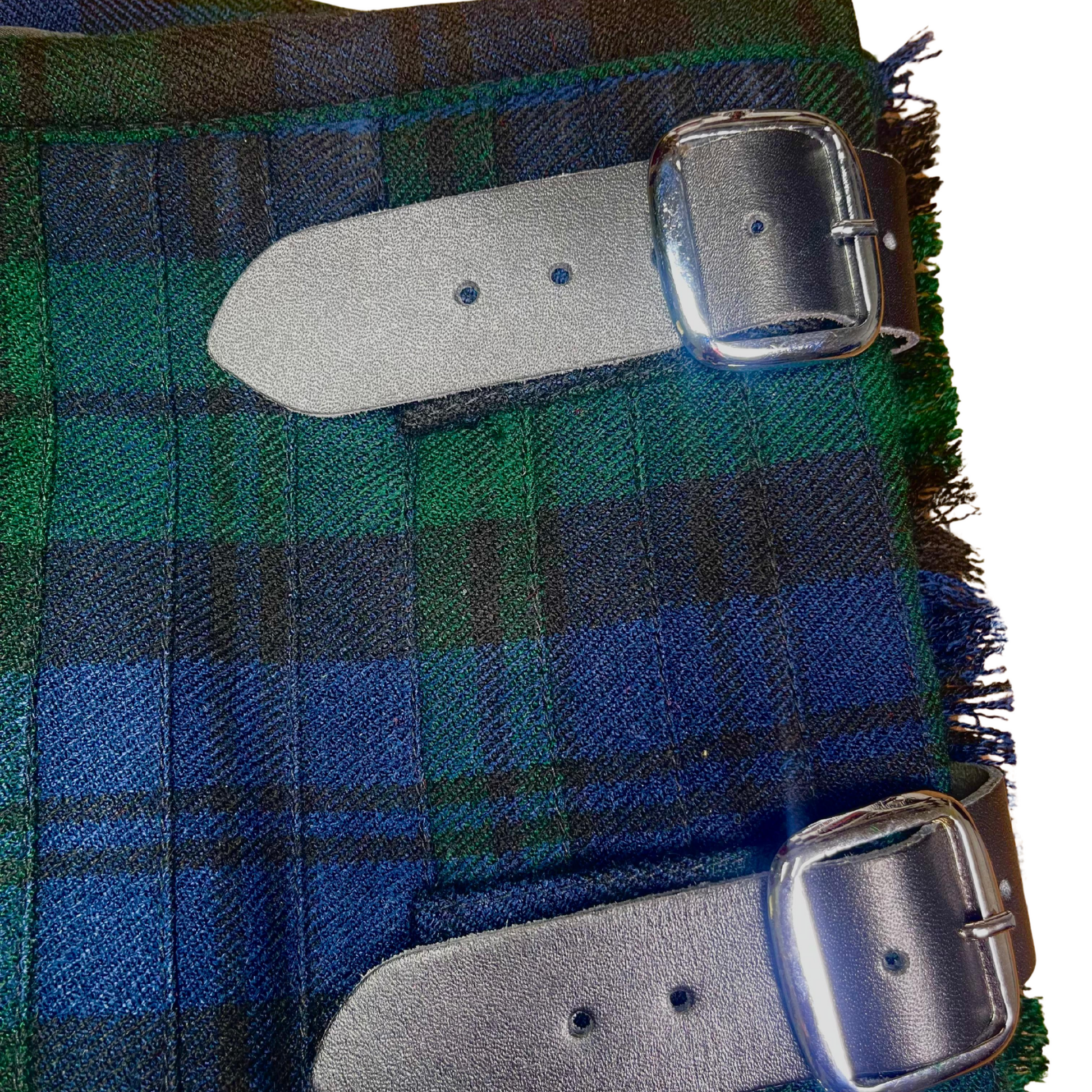 Close-up view of men’s Black Watch tartan kilt showing the traditional Scottish plaid pattern, fabric texture, and detailed Highland kilt construction.