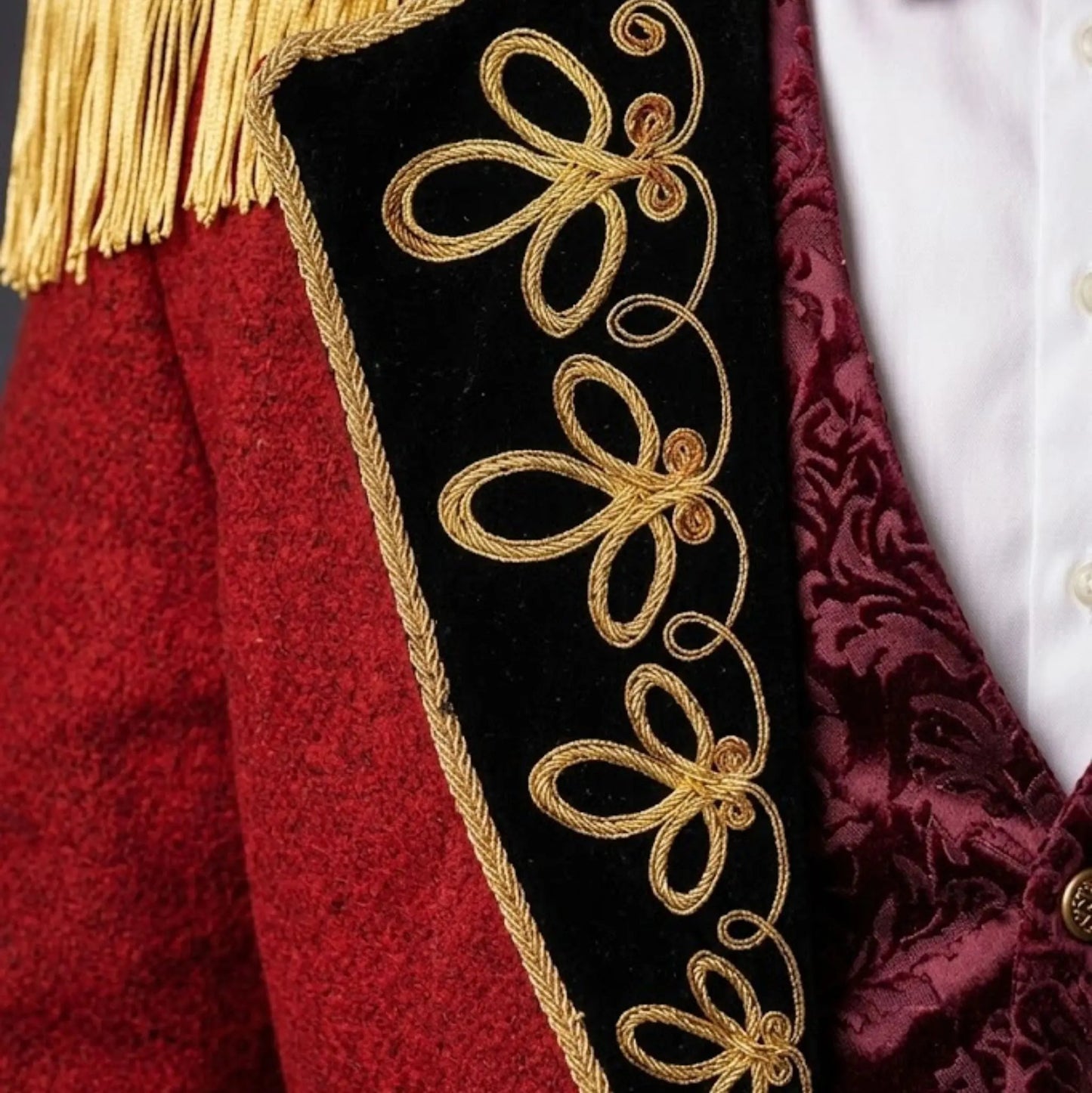 Close-up of men’s red Ringmaster tailcoat showing detailed gold embroidery, decorative buttons, and Victorian military-inspired craftsmanship.