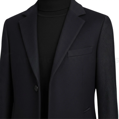 Close-up of men’s black single-breasted overcoat showing notched lapel, button detail, smooth fabric texture, and tailored slim fit finish.